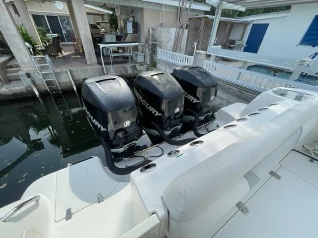 Slide: The Image of 2012 Boston Whaler 370 Outrage with triple Mercury outboard engines docked by a waterfront home. - 13