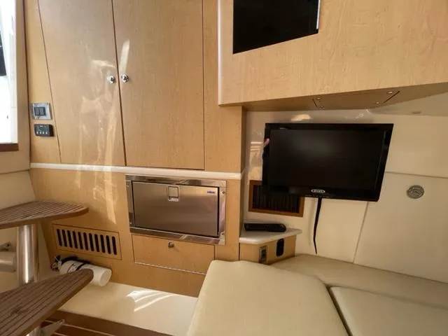 Slide: The Image of Interior of 2012 Boston Whaler 370 Outrage with TV, seating, and wooden cabinetry. - 17