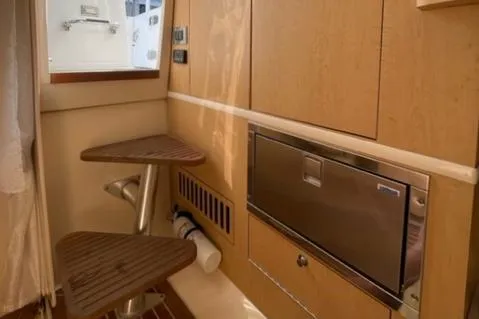 Slide: The Image of Interior of 2012 Boston Whaler 370 Outrage, featuring wooden steps and stainless steel appliance. - 23