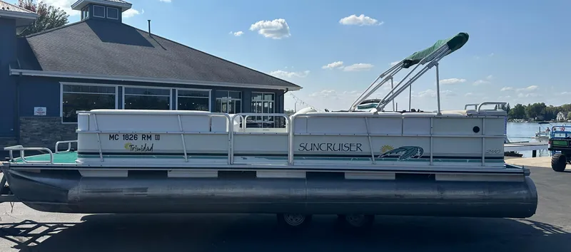 Slide: The Image of 1998 Suncruiser 240 Trinidad pontoon boat docked near a lakeside building. - 7