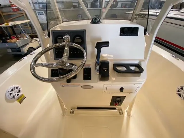 Slide: The Image of 2024 Scout 195 Sportfish boat console with steering wheel and controls in a showroom. - 5