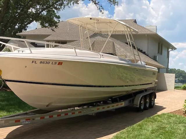 The Image of 2002 Intrepid 322 boat on trailer in front of house. - 1