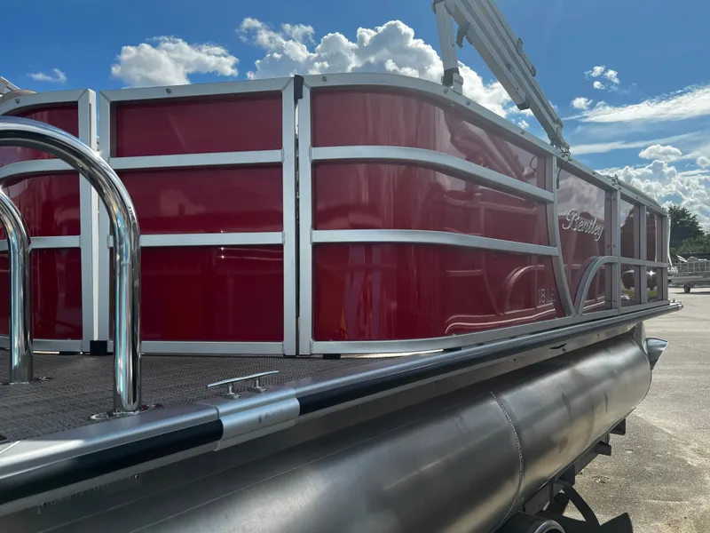 Slide: The Image of 2024 Bentley Pontoons LE 18, red exterior, docked under a sunny sky. - 5