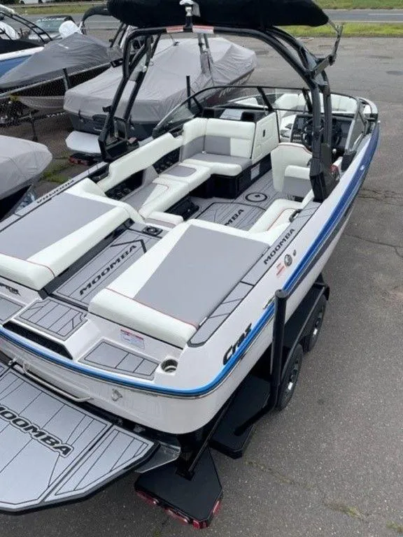 Slide: The Image of 2024 Moomba Craz boat with white and gray seating, docked on a trailer. - 6