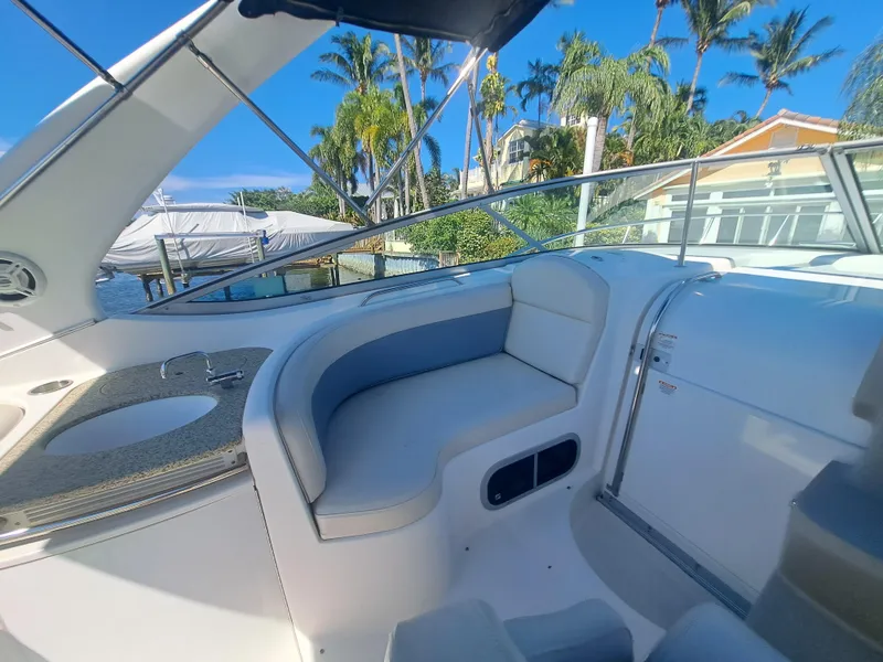 Slide: The Image of 2005 Chaparral 330 Signature Cruiser interior with seating and sink, docked near palm trees. - 6