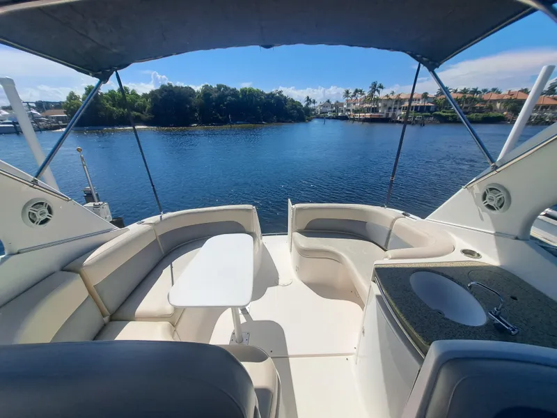 Slide: The Image of 2005 Chaparral 330 Signature Cruiser interior with seating, table, and sink, overlooking serene waterfront. - 7