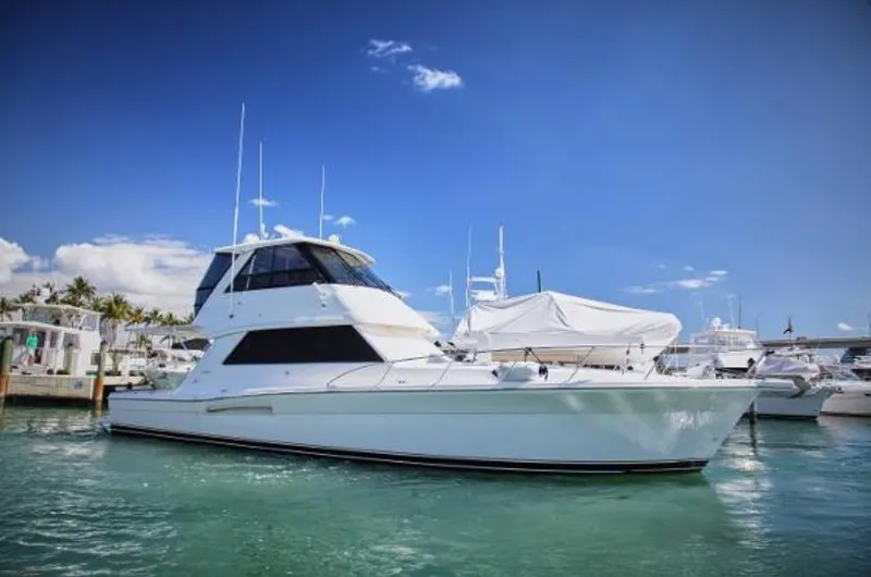 Slide: The Image of 2003 Riviera 48 yacht docked in a marina under a clear blue sky. - 0