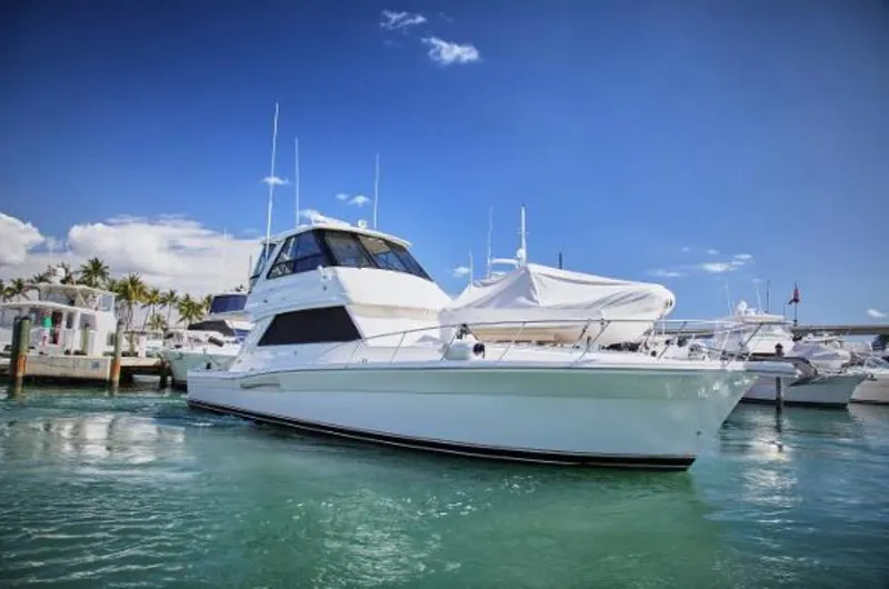 Slide: The Image of 2003 Riviera 48 yacht docked in a marina on a sunny day. - 2