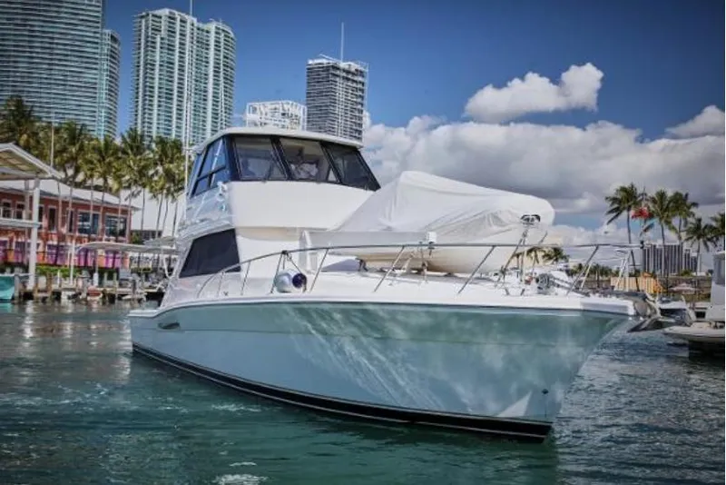 Slide: The Image of 2003 Riviera 48 yacht docked in a marina with city skyline background. - 3