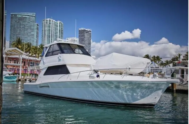 Slide: The Image of 2003 Riviera 48 yacht docked in a marina with city skyline background. - 4