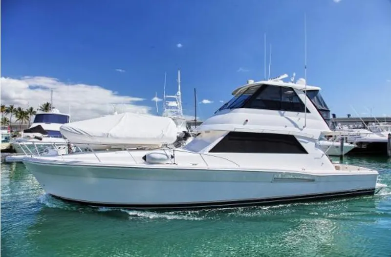 Slide: The Image of 2003 Riviera 48 yacht cruising in a marina under a clear blue sky. - 5