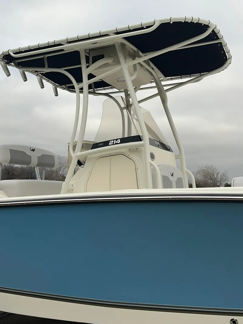 Slide: The Image of 2024 Mako 214 CC center console boat with blue hull and T-top. - 3