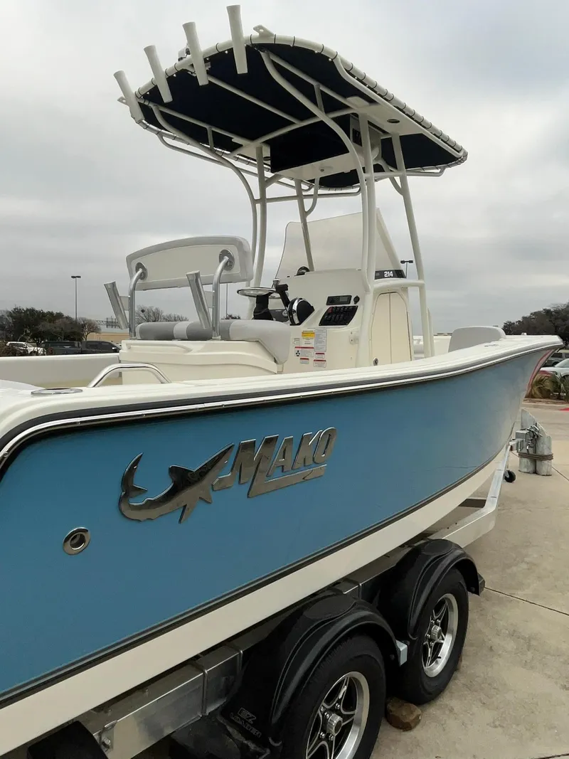Slide: The Image of 2024 Mako 214 CC boat with blue hull and T-top on trailer. - 4