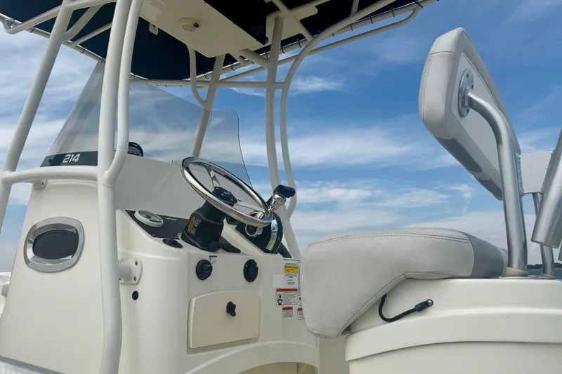 Slide: The Image of 2024 Mako 214 Center Console boat interior with steering wheel and seating under blue sky. - 3