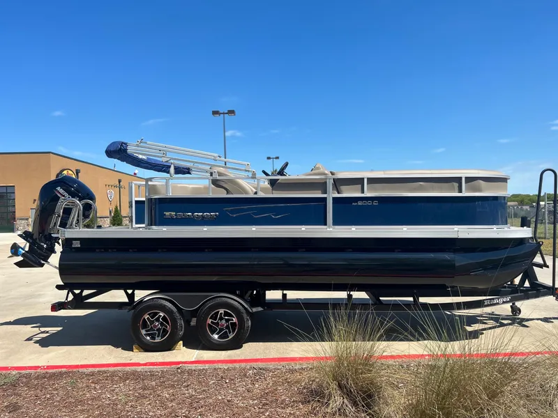 Slide: The Image of 2024 Ranger Reata 200F pontoon boat on a trailer in a parking lot. - 0