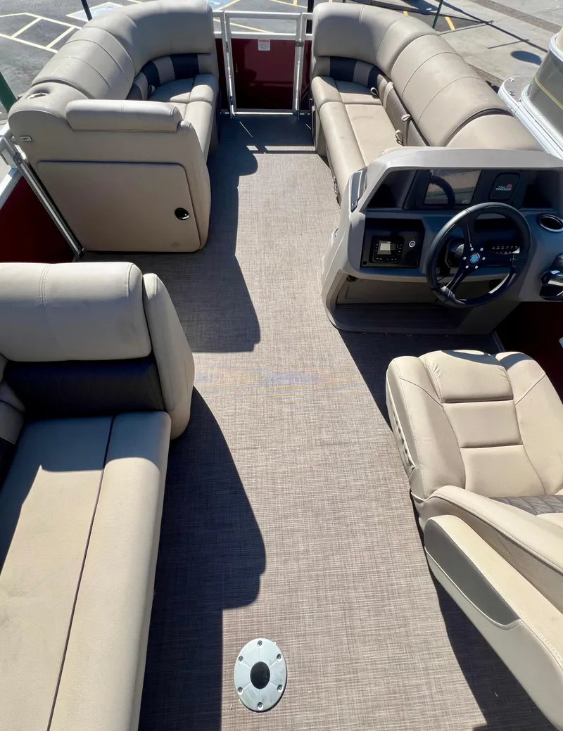 Slide: The Image of 2024 Sun Tracker Party Barge 20 DLX interior with beige seating and steering console. - 3