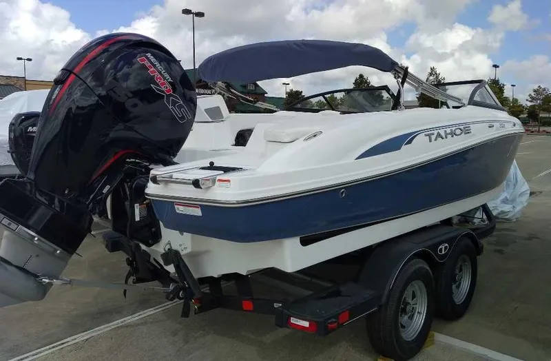 Slide: The Image of 2024 Tahoe 210 S boat on trailer with outboard motor in parking lot. - 1