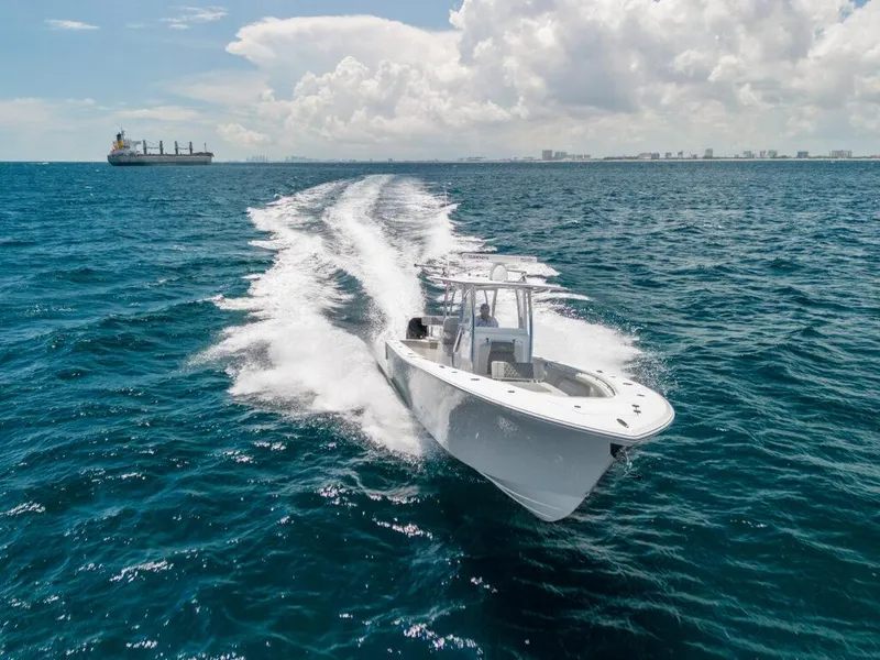 Slide: The Image of 2025 Front Runner 33 CC Custom boat cruising on open ocean with city skyline in background. - 13