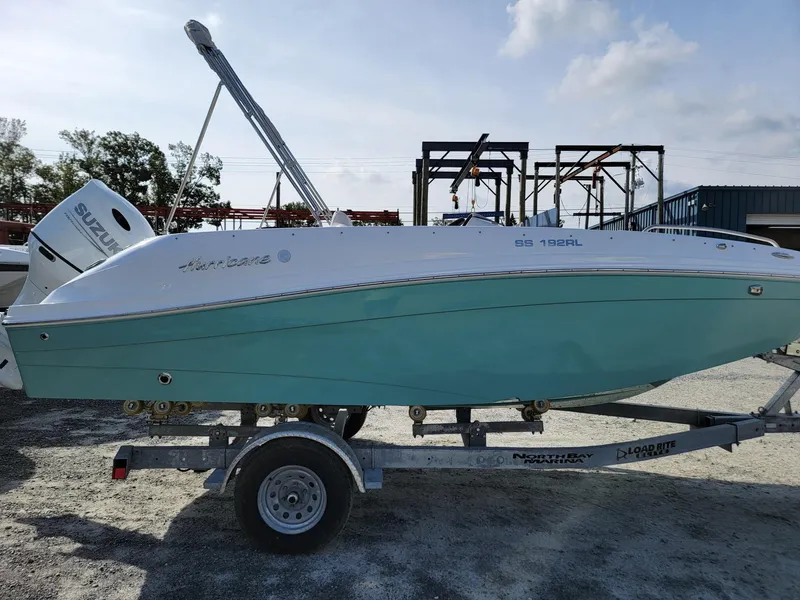 Slide: The Image of 2024 Hurricane SunDeck Sport 192 RL OB boat on a trailer in a marina. - 5