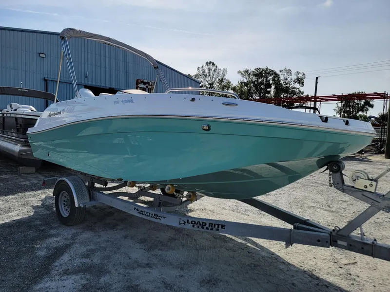 Slide: The Image of 2024 Hurricane SunDeck Sport 192 RL OB boat on a trailer in a marina. - 6