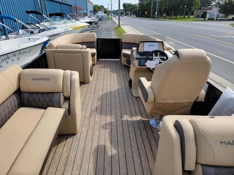 Slide: The Image of 2024 Harris Sunliner 210 pontoon boat with beige seating and wooden deck. - 26