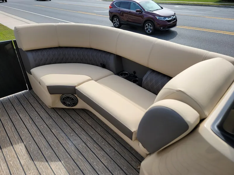 Slide: The Image of 2024 Harris Sunliner 210 boat with beige and gray seating on a wooden deck. - 32