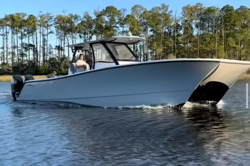 The Image of 2024 Front Runner 37 Catamaran cruising on a calm lake with forested background. - 0