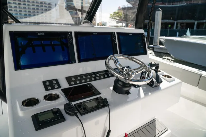 Slide: The Image of Control panel of 2026 Front Runner 37 Catamaran with multiple screens and steering wheel. - 2