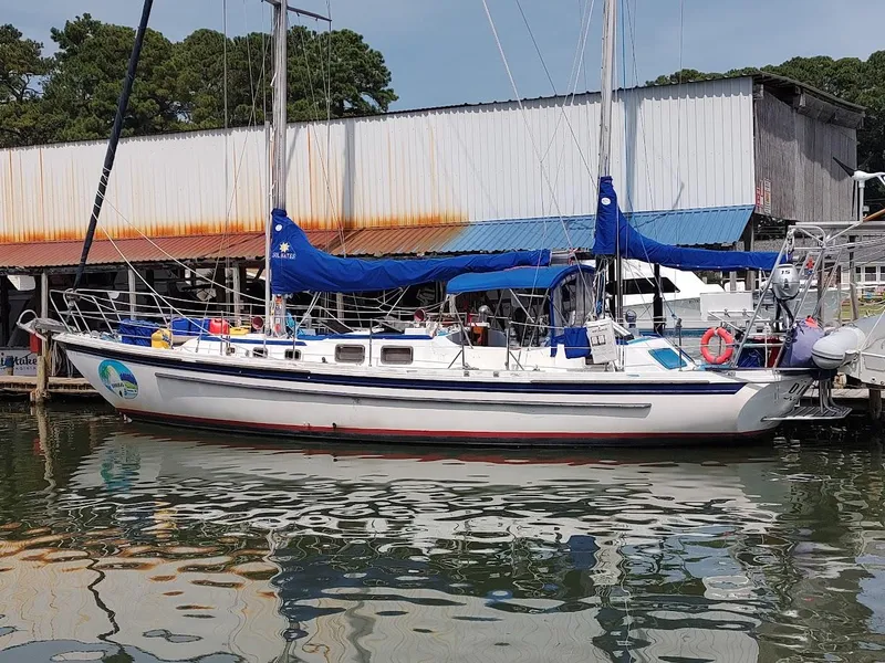 Slide: The Image of 1981 Bruce Roberts 450 sailboat docked at marina with blue covers and calm water reflection. - 3