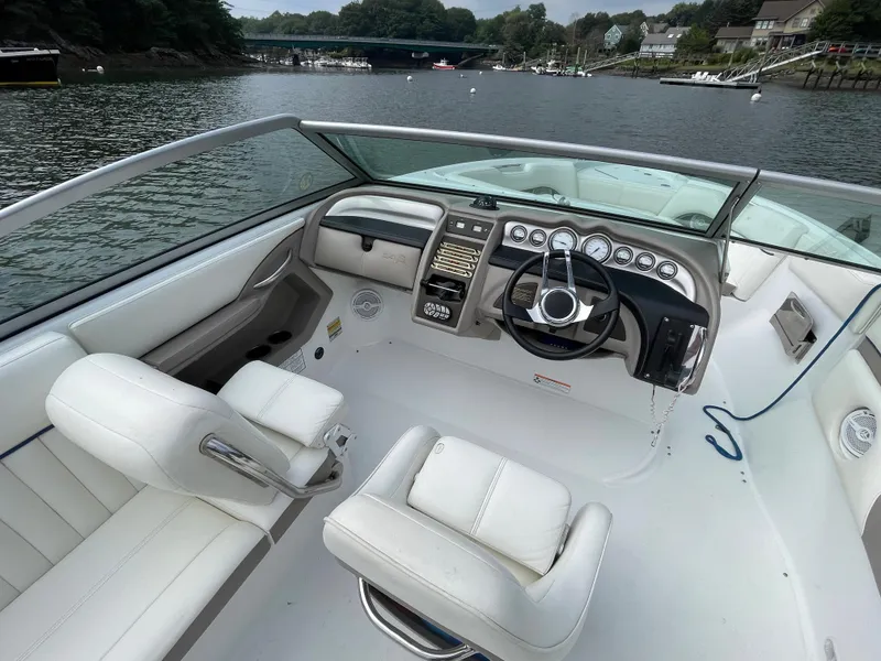 Slide: The Image of 2006 Cobalt 24SX boat interior with white seating and steering console on a calm river. - 13