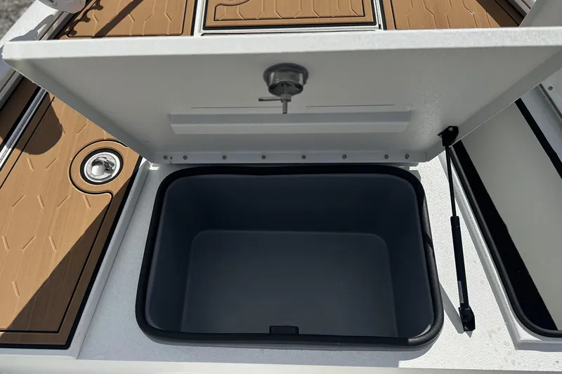 Slide: The Image of Open storage compartment on 2026 Avid 19 FSX boat with brown deck. - 10