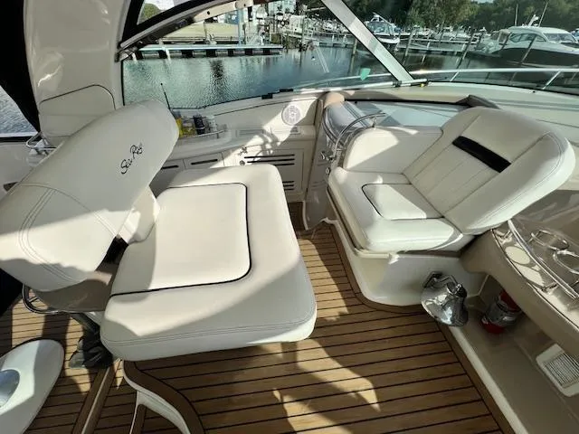 Slide: The Image of 2005 Sea Ray 500 Sundancer cockpit with white seating and wooden flooring, docked at marina. - 26