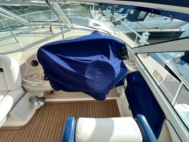Slide: The Image of 2005 Sea Ray 500 Sundancer cockpit with blue cover, featuring teak flooring and white seating. - 39