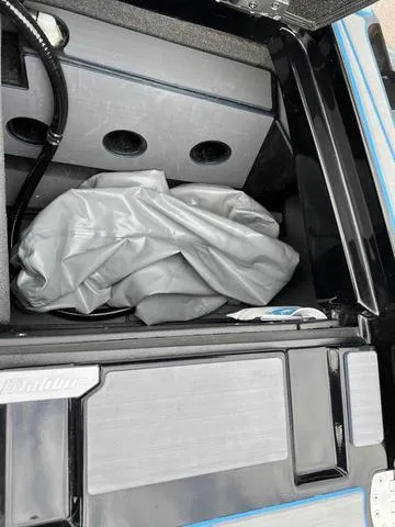 Slide: The Image of 2021 Malibu M220 storage compartment with gray cover. - 15