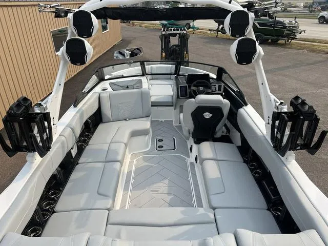 Slide: The Image of 2024 Malibu 23 LSV boat interior with white and gray seating, advanced sound system, and modern dashboard. - 10