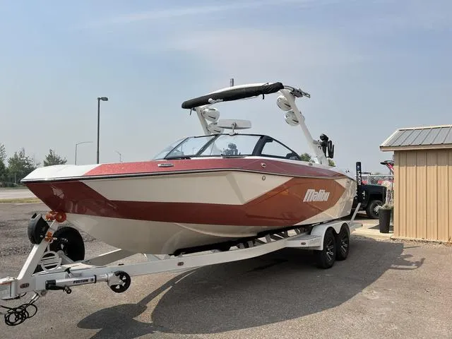 Slide: The Image of 2024 Malibu 23 LSV boat on trailer, red and white exterior, parked outdoors. - 5