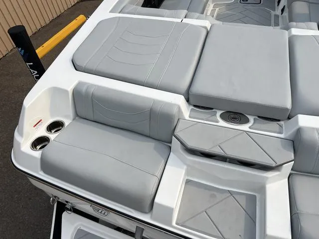 Slide: The Image of 2024 Malibu 23 LSV boat interior with gray cushioned seating and cup holders. - 9