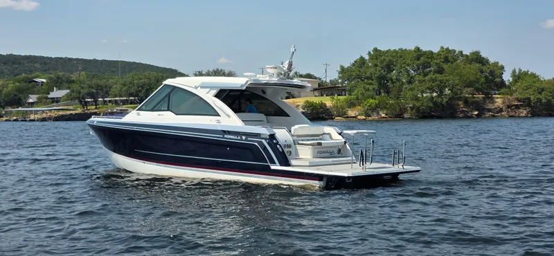 Slide: The Image of 2021 Formula 380 Super Sport Crossover boat cruising on a lake with scenic background. - 1