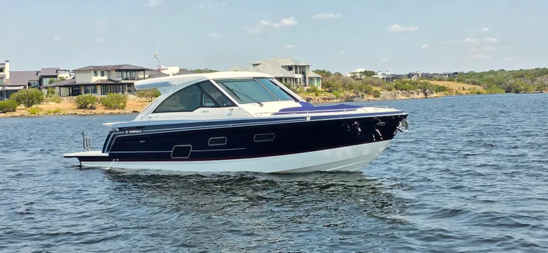 Slide: The Image of 2021 Formula 380 Super Sport Crossover boat on a lake near modern homes. - 4