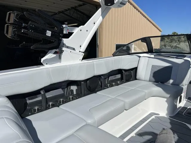 Slide: The Image of 2024 Malibu 23 MXZ boat interior with white leather seating and cup holders. - 15
