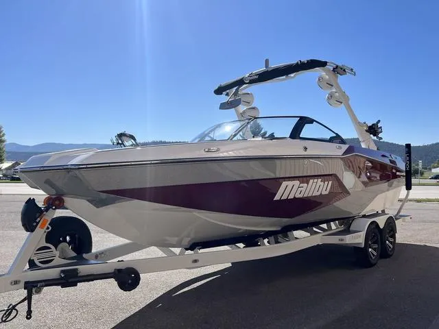 Slide: The Image of 2024 Malibu 23 MXZ boat on trailer under clear blue sky. - 5