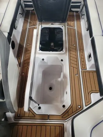 Slide: The Image of 2015 Nautique G23 boat interior with open storage compartments and teak flooring. - 12