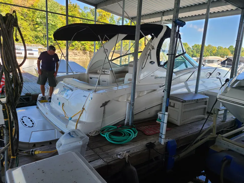 Slide: The Image of 2002 Sea Ray 320 Sundancer docked in a covered marina with a person standing nearby. - 17