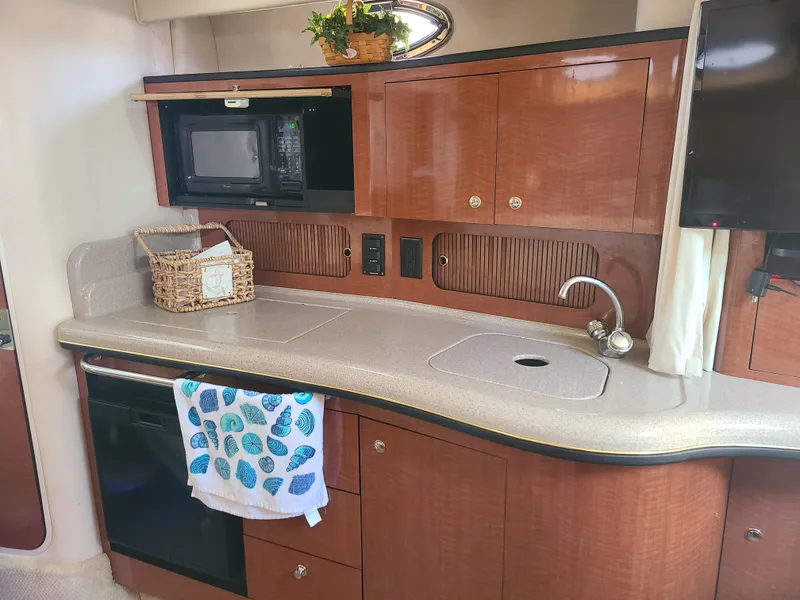 Slide: The Image of 2002 Sea Ray 320 Sundancer galley with microwave, sink, and storage cabinets. - 42
