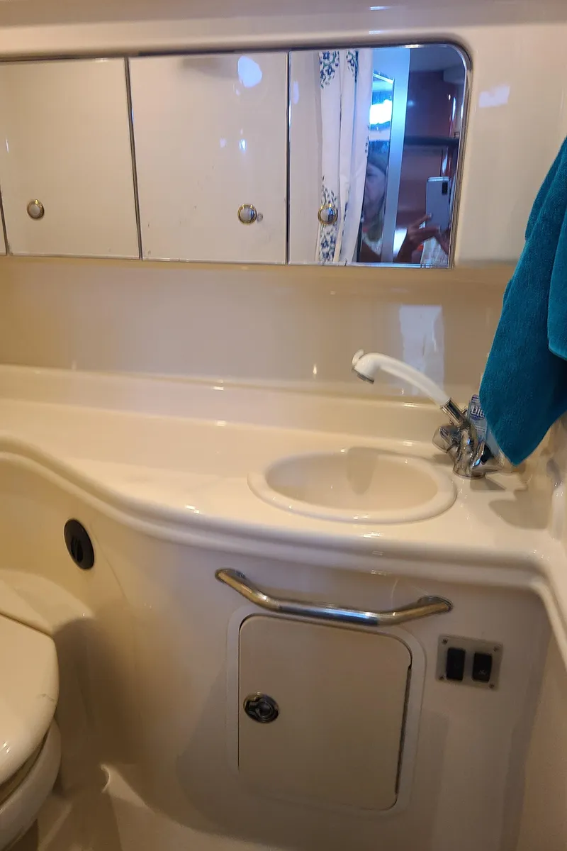 Slide: The Image of 2002 Sea Ray 320 Sundancer bathroom with sink, mirror, and storage cabinets. - 43
