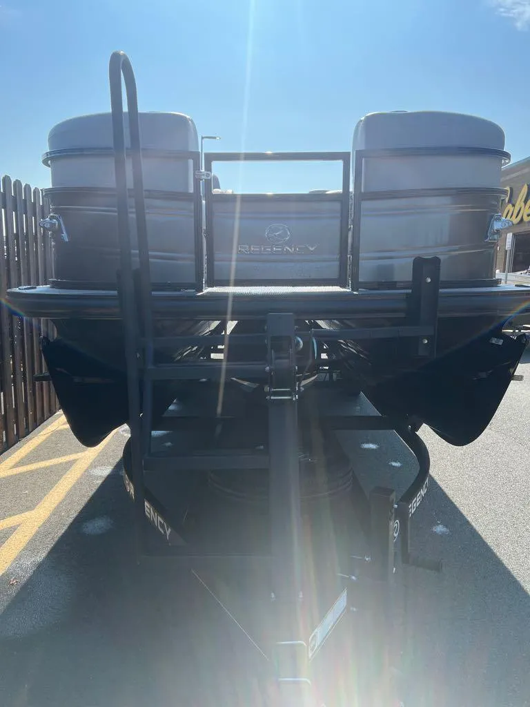 Slide: The Image of 2023 Regency 250 LE3 pontoon boat on a trailer in a parking lot. - 4