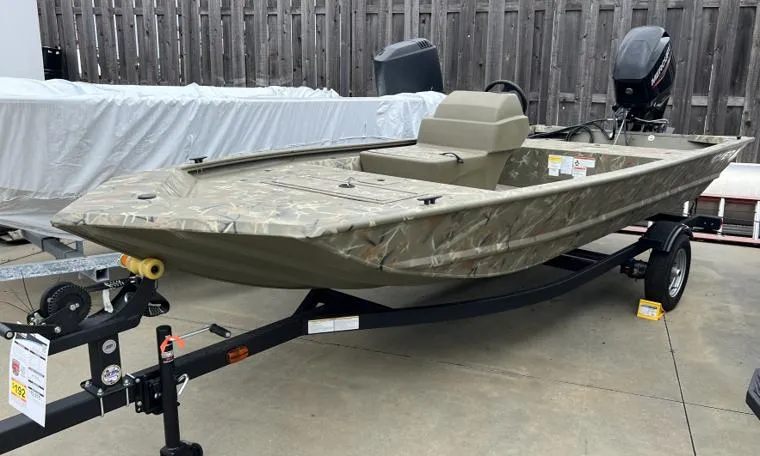 The Image of 2024 Tracker Grizzly 1648 SC boat on trailer, camo design, outboard motor, parked outdoors. - 0