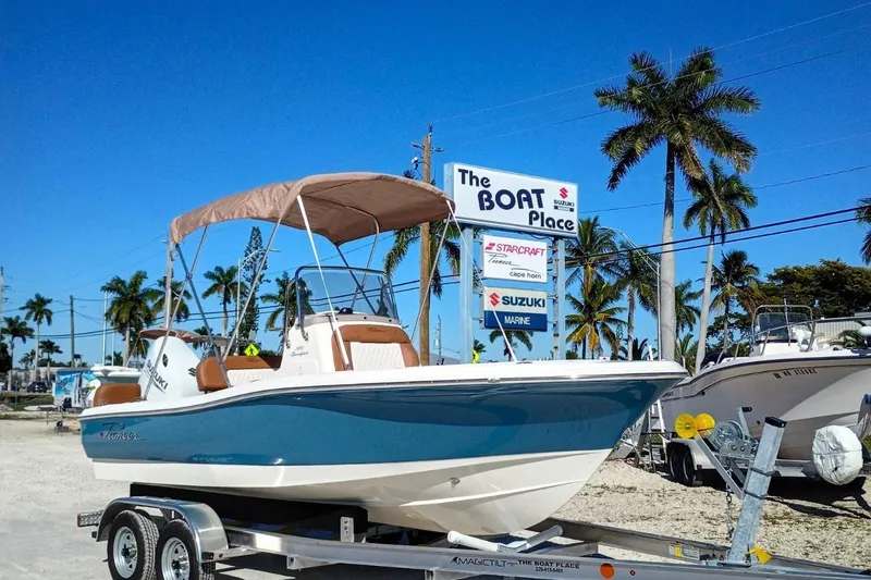 The Image of 2026 Pioneer 180 Sportfish boat on trailer at dealership with palm trees. - 0