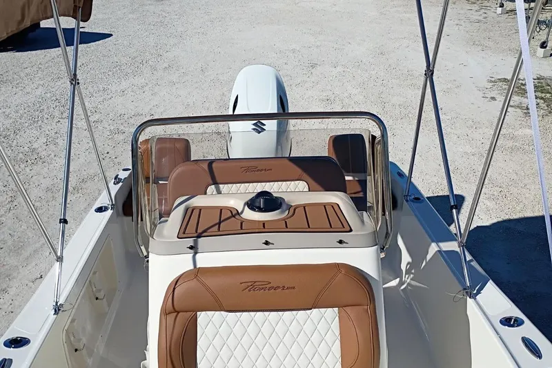 Slide: The Image of 2026 Pioneer 180 Sportfish boat interior with brown and white seating, clear windshield, and Suzuki engine. - 18