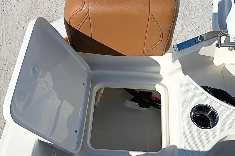 Slide: The Image of Open storage compartment on 2026 Pioneer 180 Sportfish boat with tan seat and cup holder. - 27